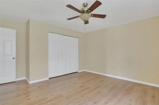 an empty room with wooden floor and a ceiling fan
