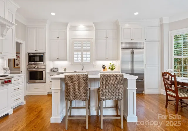 a kitchen with stainless steel appliances granite countertop a stove a refrigerator a kitchen island with a dining table and chairs