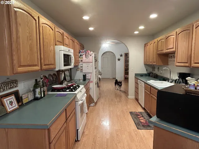 a kitchen with stainless steel appliances granite countertop a stove top oven a sink dishwasher a refrigerator and cabinets with wooden floor