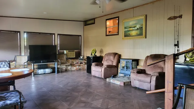 a living room with furniture a flat screen tv and floor to ceiling window