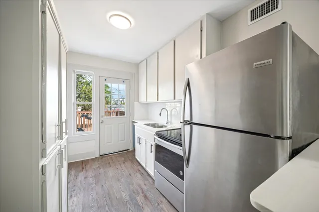 a kitchen with a refrigerator a sink and dishwasher with wooden floor