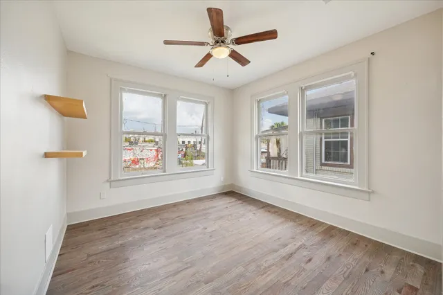 a view of an empty room with a window and wooden floor