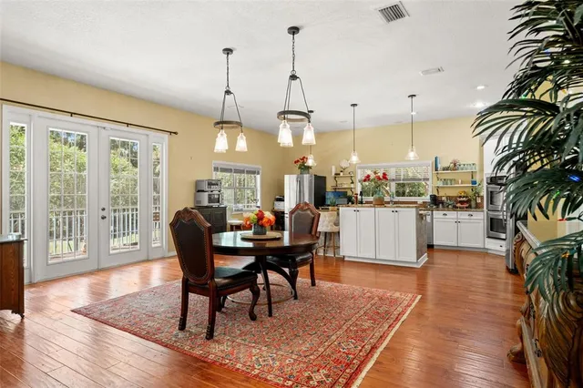 a living room with furniture a dining table a large window and wooden floor