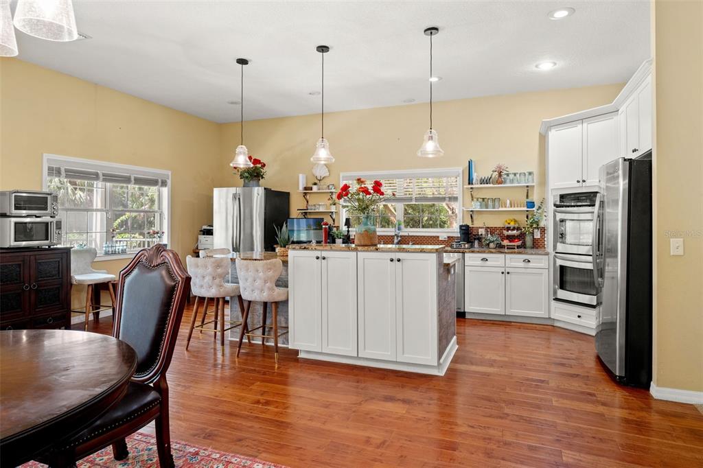 4270 Southeast 193rd Place Yankeetown, FL 34498 - Photo 6 of 42 a kitchen with stainless steel appliances kitchen island granite countertop a stove a sink a refrigerator a dining table and chairs with wooden floor