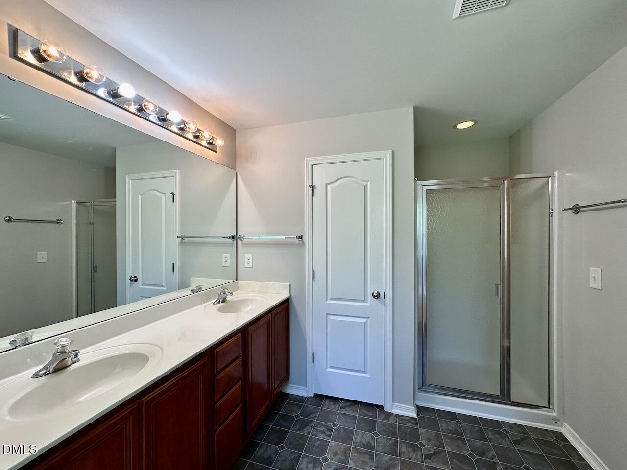8208 Stone Cellar Drive Raleigh, NC 27613 - Photo 22 of 34 a spacious bathroom with a double vanity sink a mirror and a shower