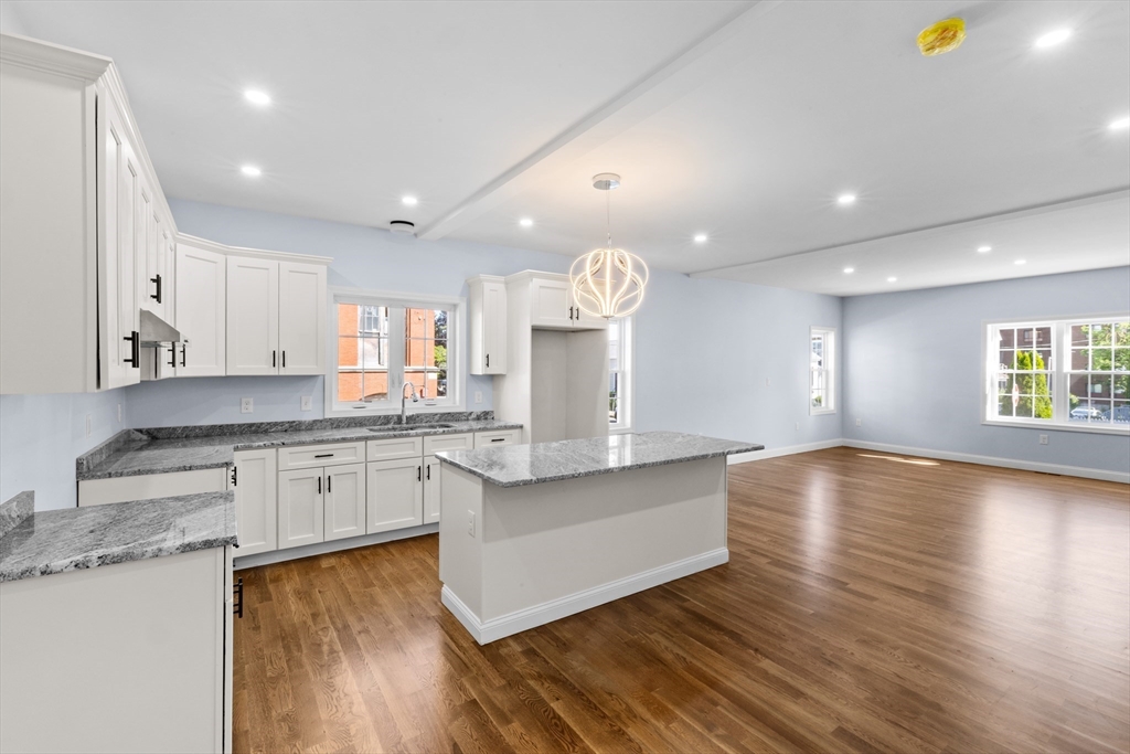 489 Spring Street Fall River, MA 02721 - Photo 11 of 42 a large kitchen with granite countertop a stove top oven a sink a dining table and chairs with wooden floor