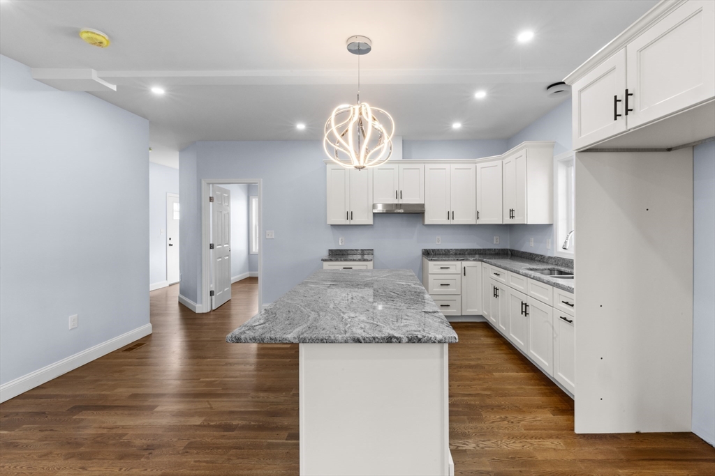 489 Spring Street Fall River, MA 02721 - Photo 15 of 42 a kitchen with kitchen island granite countertop a stove a sink and white cabinets