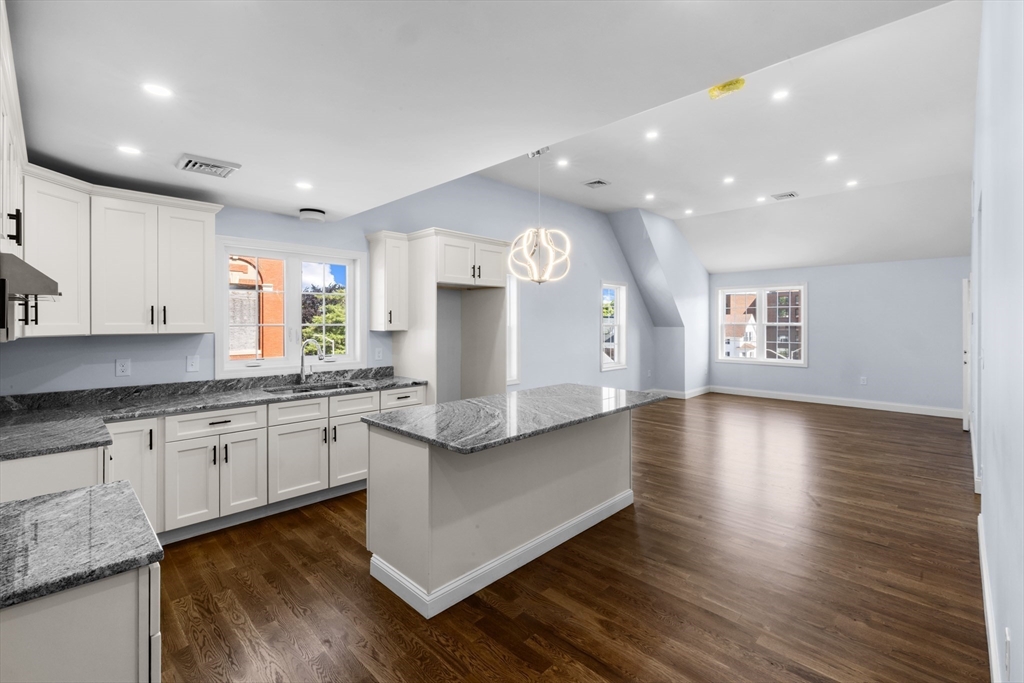 489 Spring Street Fall River, MA 02721 - Photo 23 of 42 a large kitchen with stainless steel appliances granite countertop a large stove a sink and dishwasher with wooden floor