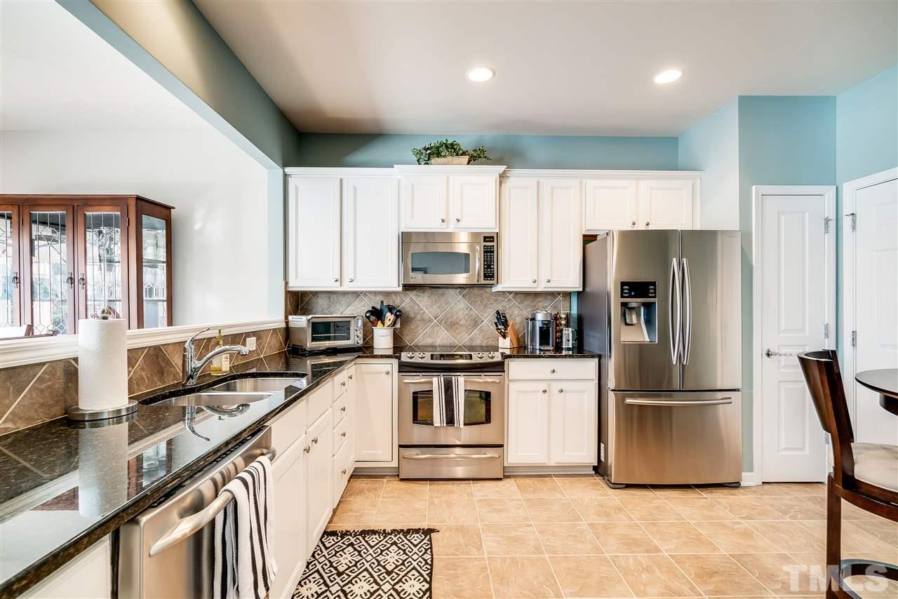 8317 Deckbar Place Raleigh, NC 27617 - Photo 12 of 25 featuring granite countertops, tile floor, tile backsplash, ss appliances, and panty.