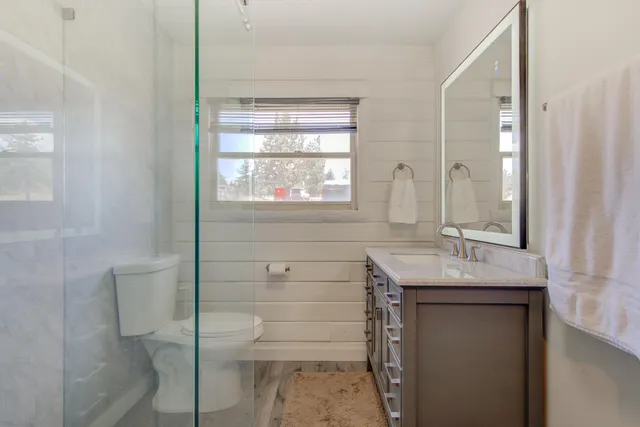 a bathroom with a granite countertop sink a toilet and shower