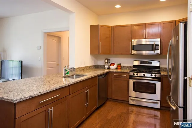 a kitchen with stainless steel appliances granite countertop a sink a stove and a microwave