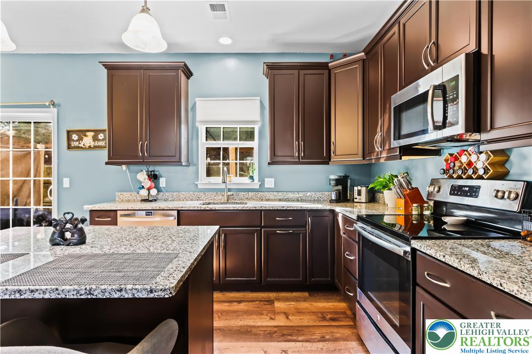 2260 Rising Hill Road Whitehall, PA 18052 - Photo 12 of 30 a kitchen with granite countertop a stove a sink dishwasher and cabinets with wooden floor