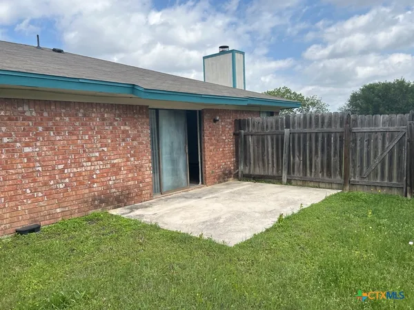 a view of a backyard with brick wall and wooden fence