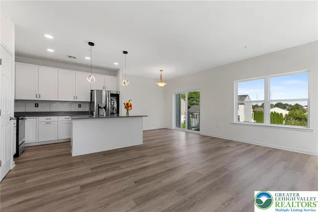 a living room with furniture white walls and kitchen view