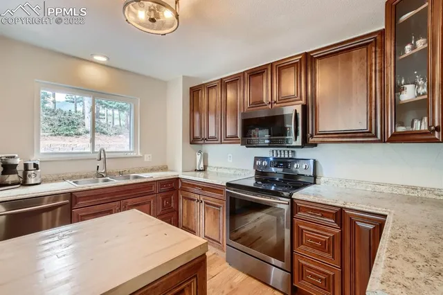 a kitchen with granite countertop a sink stove and microwave