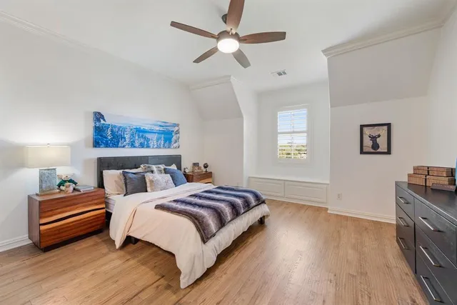 a bedroom with a bed wooden floor and a ceiling fan