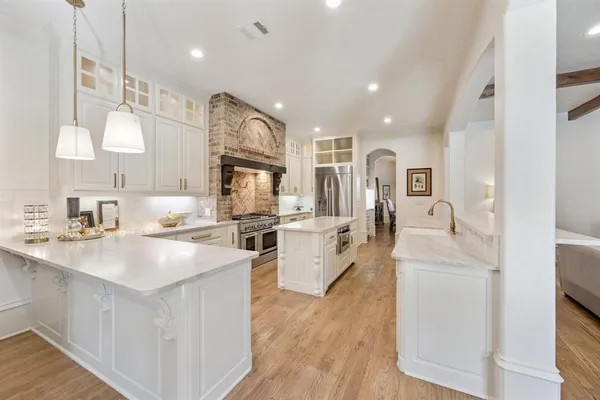 a kitchen that has a lot of white cabinets and stainless steel appliances