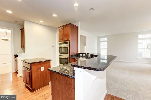 a kitchen with kitchen island granite countertop wooden cabinets and a refrigerator
