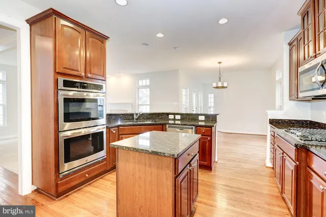 a kitchen with kitchen island a counter top space cabinets and stainless steel appliances