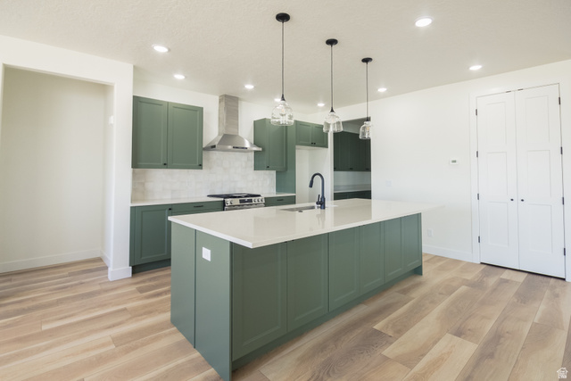 3322 250 S Street Vernal, UT 84078 - Photo 6 of 37 Modern kitchen featuring an expansive center island with a white countertop, sage green cabinetry, wood-finish flooring, a stainless steel range hood, and pendant lighting fixtures