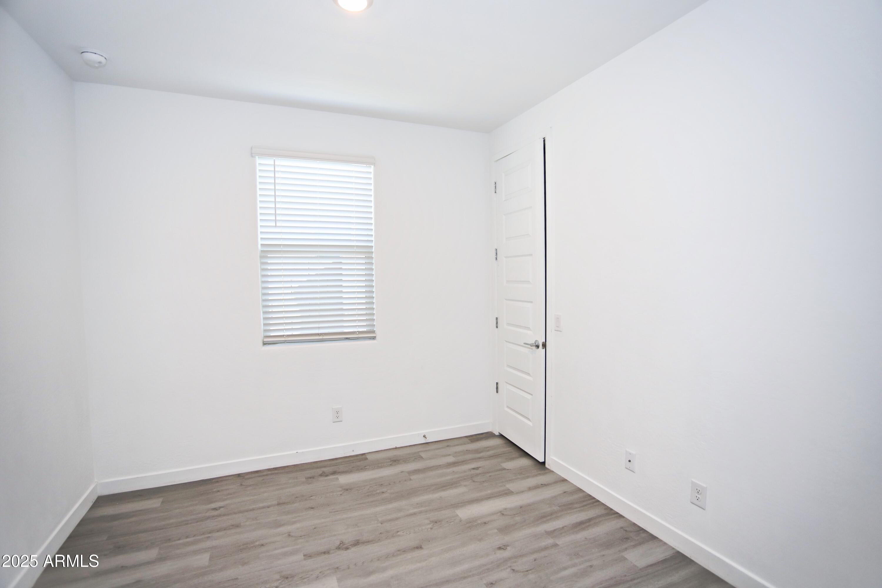 1535 West Corral Road Phoenix, AZ 85041 - Photo 12 of 39 an empty room with wooden floor and windows