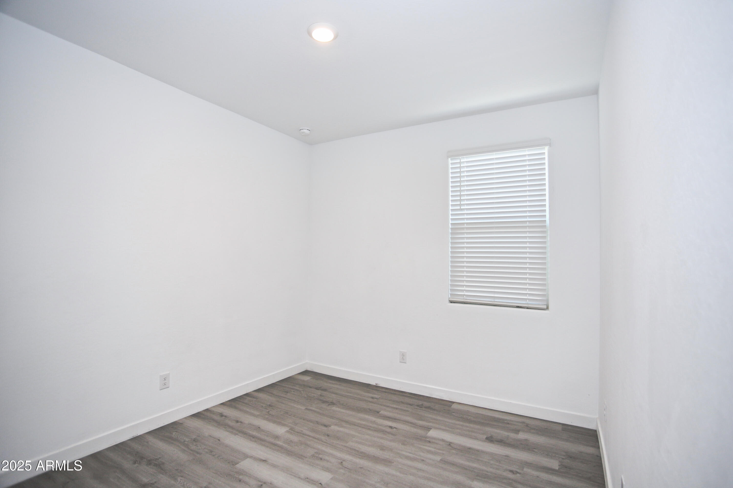 1535 West Corral Road Phoenix, AZ 85041 - Photo 8 of 39 an empty room with wooden floor and windows