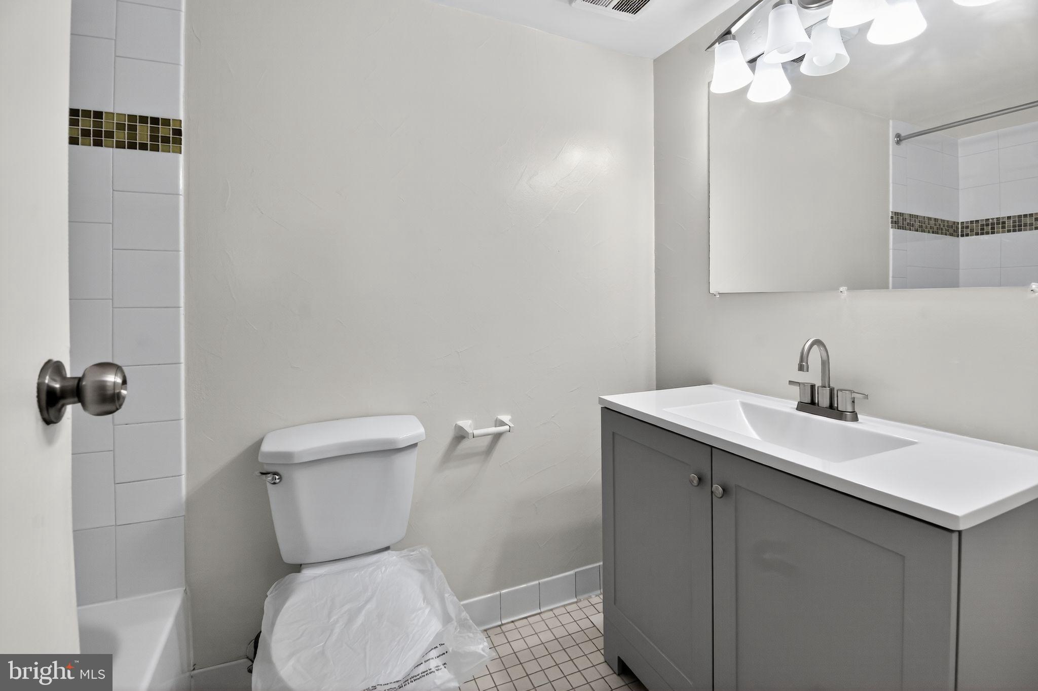 7957 Riggs Road, Unit 7 Hyattsville, MD 20783 - Photo 11 of 15 a bathroom with a toilet a sink a mirror and vanity