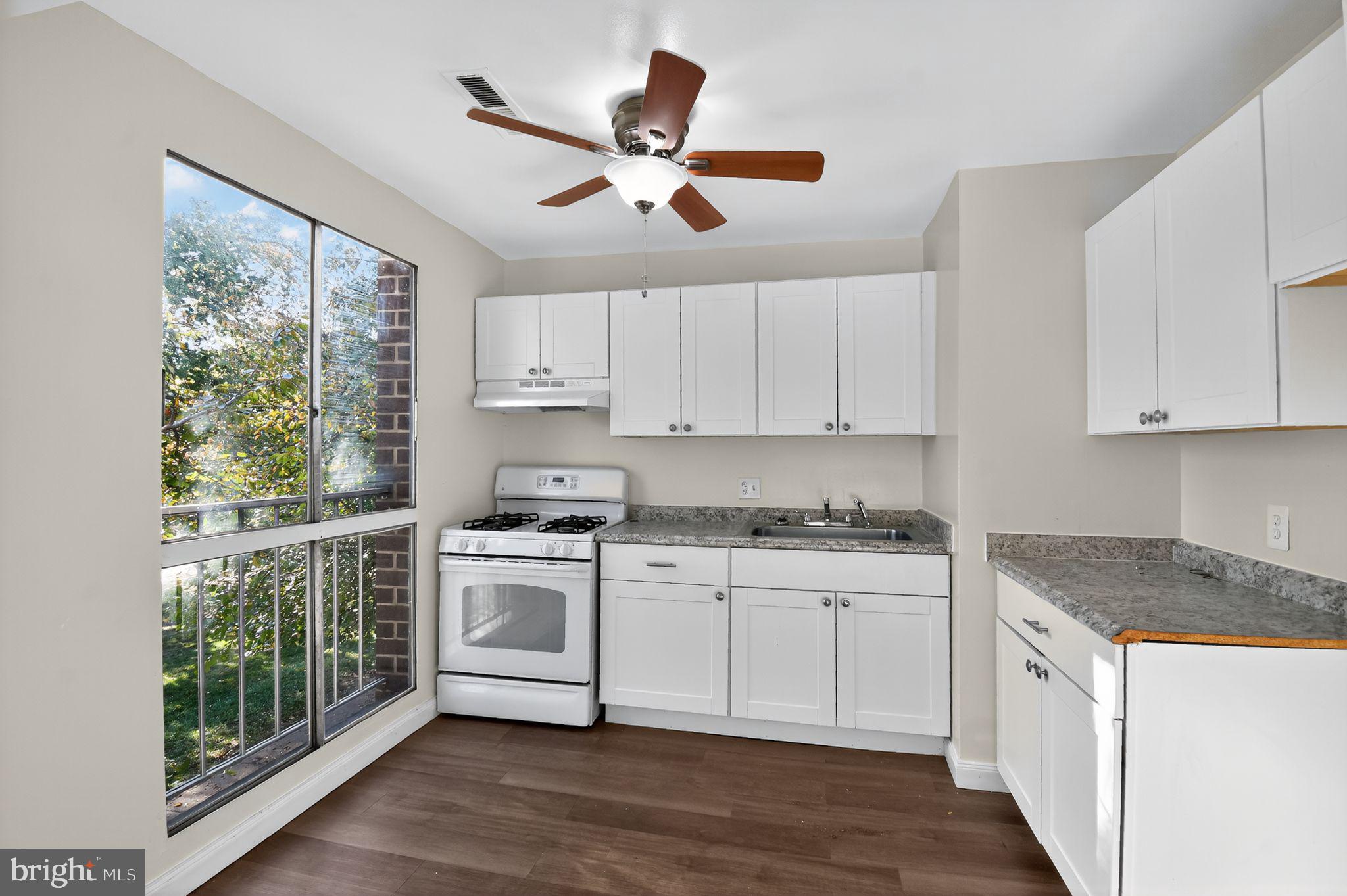 7957 Riggs Road, Unit 7 Hyattsville, MD 20783 - Photo 4 of 15 a kitchen with a stove a sink and white cabinets