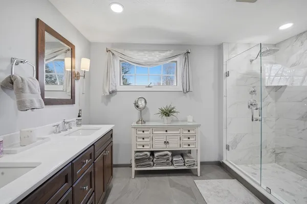 a spacious bathroom with a double vanity sink a mirror and a shower