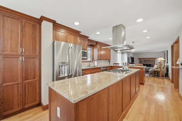 a kitchen with stainless steel appliances granite countertop a refrigerator a stove and a wooden floors