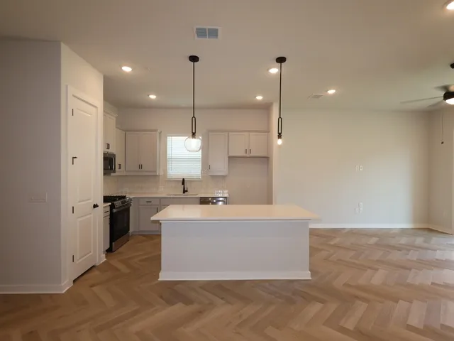 a view of a kitchen with kitchen island a counter top space a sink stainless steel appliances and cabinets