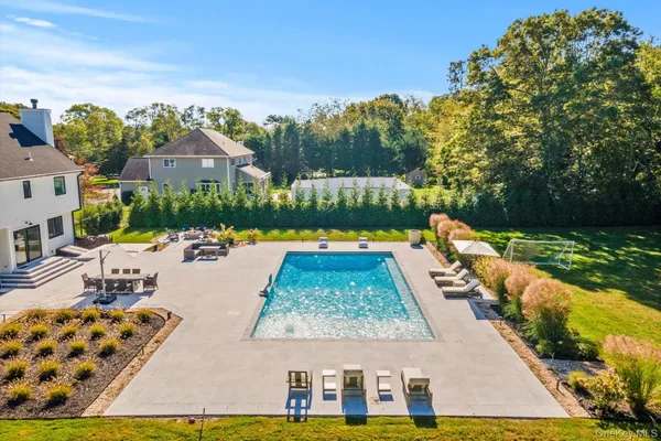 a view of swimming pool with seating area and trees in the background