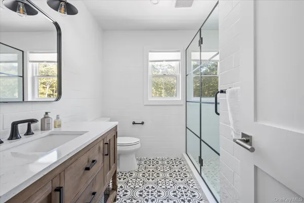 a bathroom with a sink a toilet a mirror a window and vanity