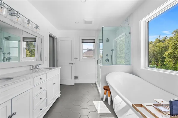 a spacious bathroom with double vanity a mirror a bathtub and a shower