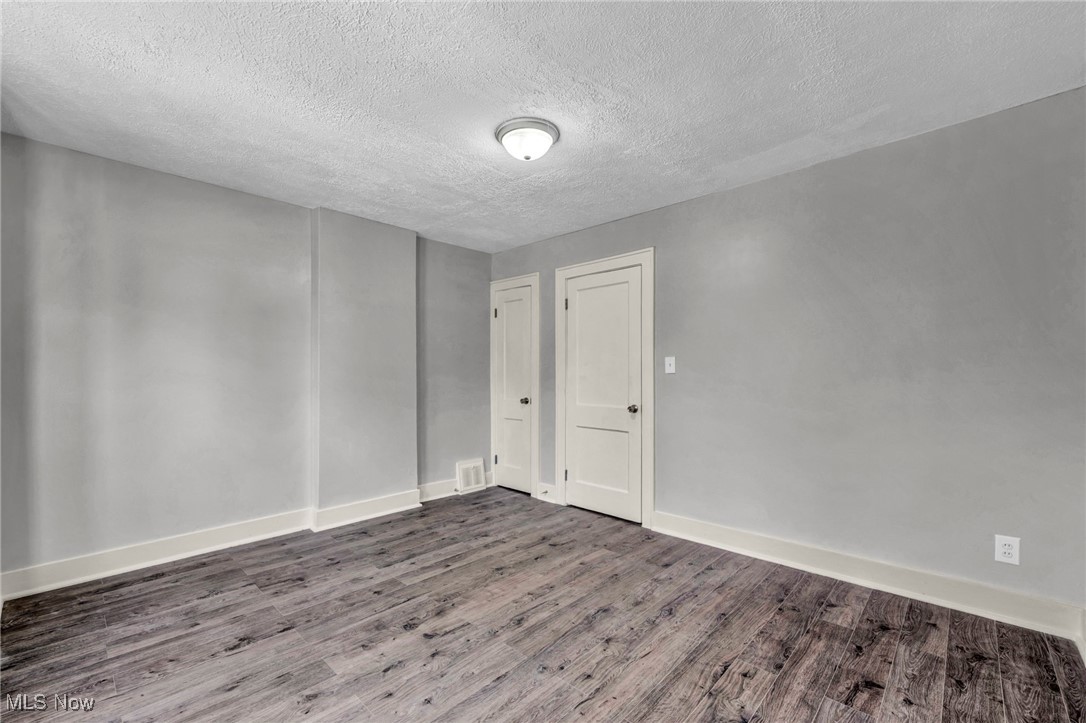 3239 Sycamore Road Cleveland, OH 44118 - Photo 21 of 49 Unfurnished room with baseboards, a textured ceiling, visible vents, and wood finished floors