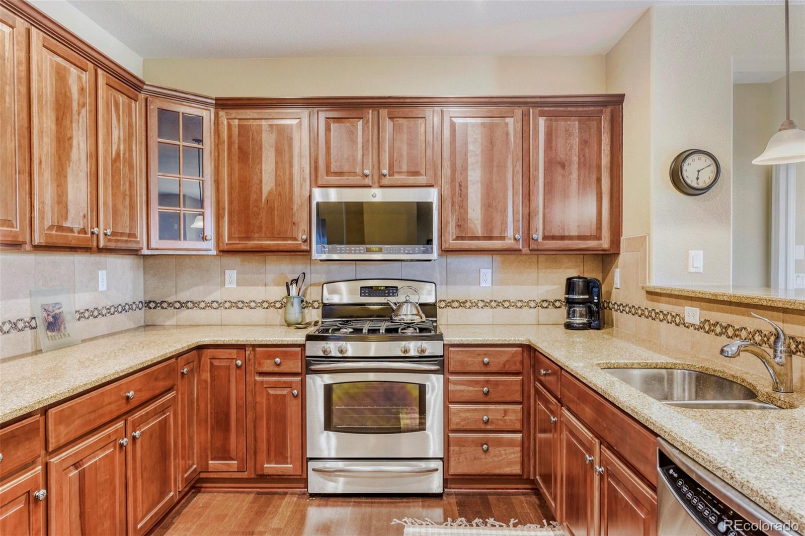 3355 Cascina Circle, Unit B Highlands Ranch, CO 80126 - Photo 12 of 28 a kitchen with granite countertop a sink a stove oven and cabinets