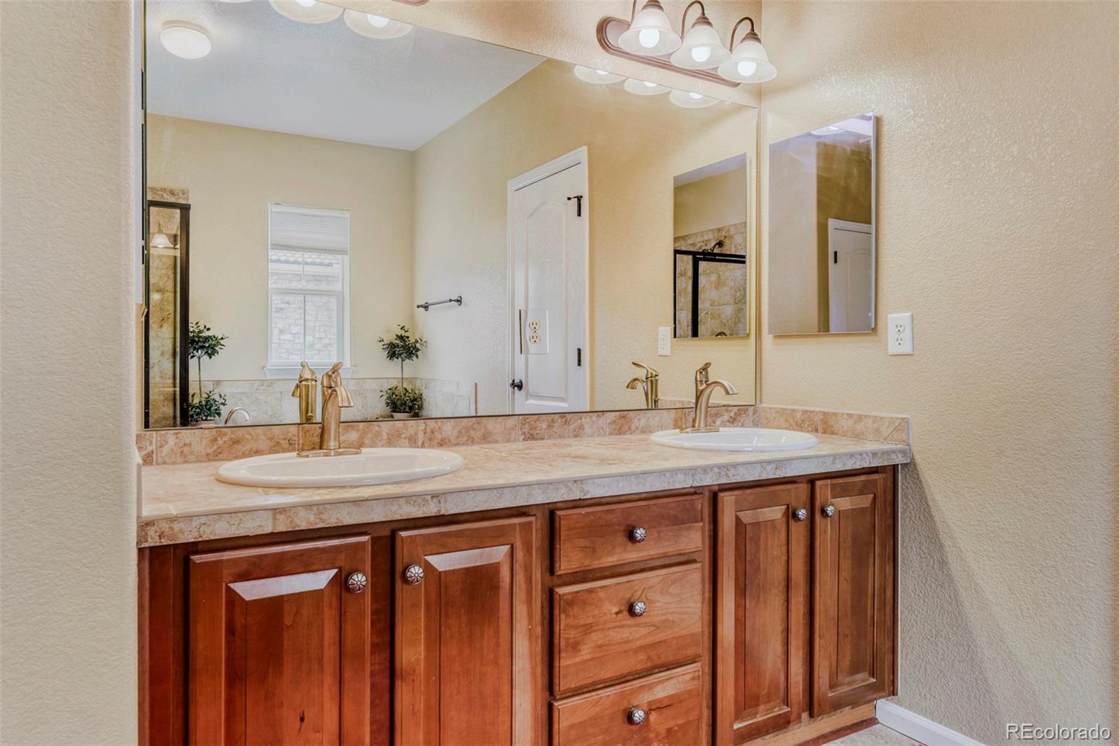 3355 Cascina Circle, Unit B Highlands Ranch, CO 80126 - Photo 20 of 28 a bathroom with a granite countertop sink a large mirror and a