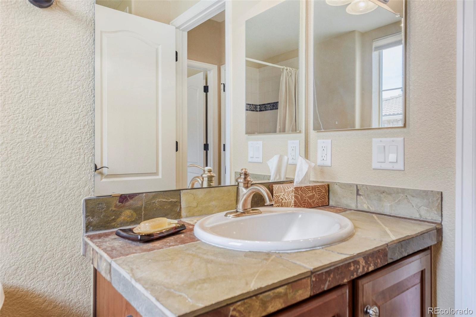 3355 Cascina Circle, Unit B Highlands Ranch, CO 80126 - Photo 26 of 28 a bathroom with a granite countertop sink and a mirror