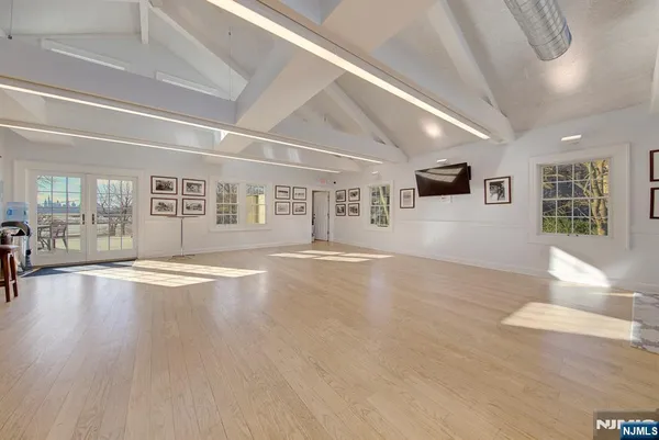 a view of an empty room with window and wooden floor