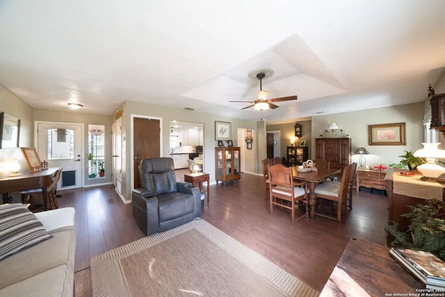 a living room with furniture kitchen view and a wooden floor