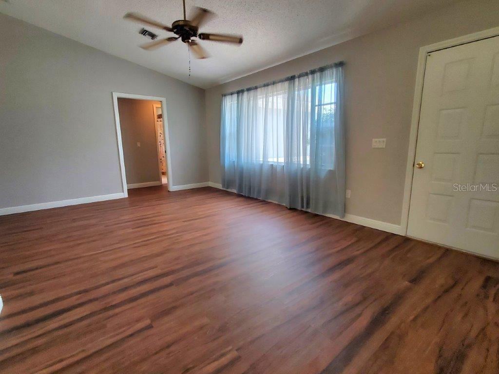 26014 Ocelot Lane Punta Gorda, FL 33983 - Photo 27 of 35 an empty room with wooden floor chandelier fan and windows