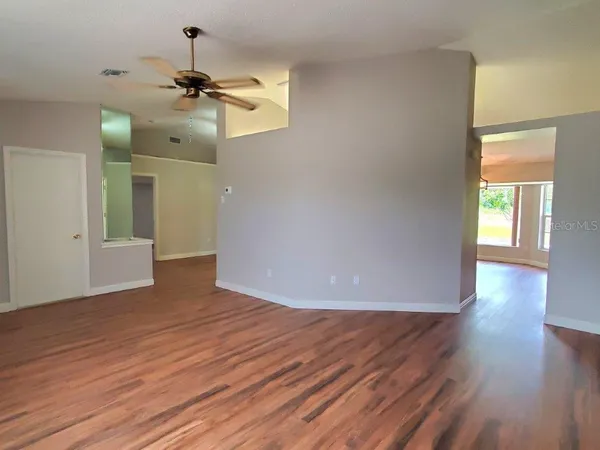 a view of empty room with wooden floor and ceiling fan