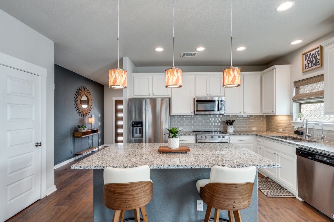 125 Syrah Court Leander, TX 78641 - Photo 10 of 25 a kitchen with stainless steel appliances kitchen island granite countertop a sink refrigerator and cabinets