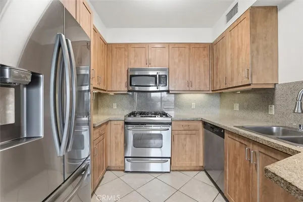 a kitchen with granite countertop a refrigerator stove and microwave