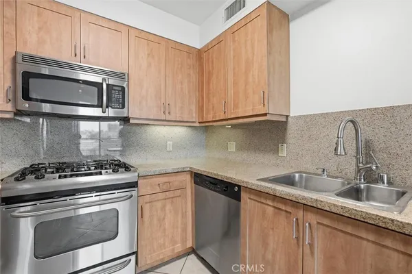 a kitchen with stainless steel appliances granite countertop a sink stove and microwave