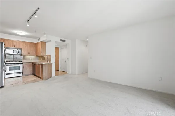a view of kitchen with refrigerator and white cabinets