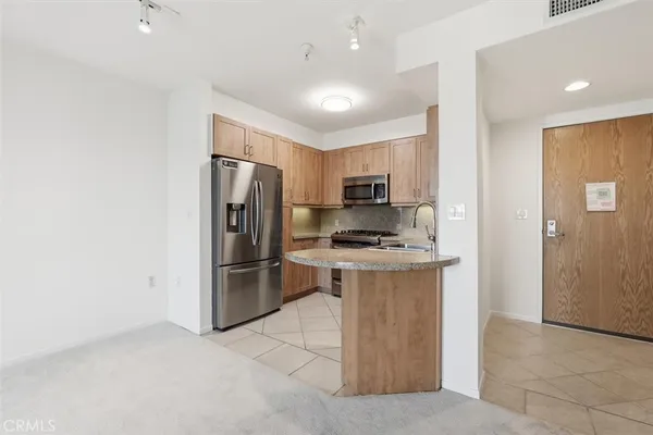 a kitchen with stainless steel appliances granite countertop a refrigerator oven a sink dishwasher and white cabinets with wooden floor