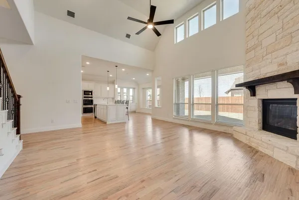a view of an empty room with wooden floor and a fireplace