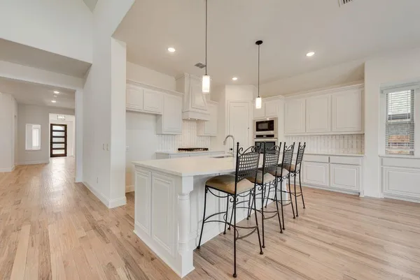 a kitchen with stainless steel appliances a dining table chairs stove refrigerator and cabinets
