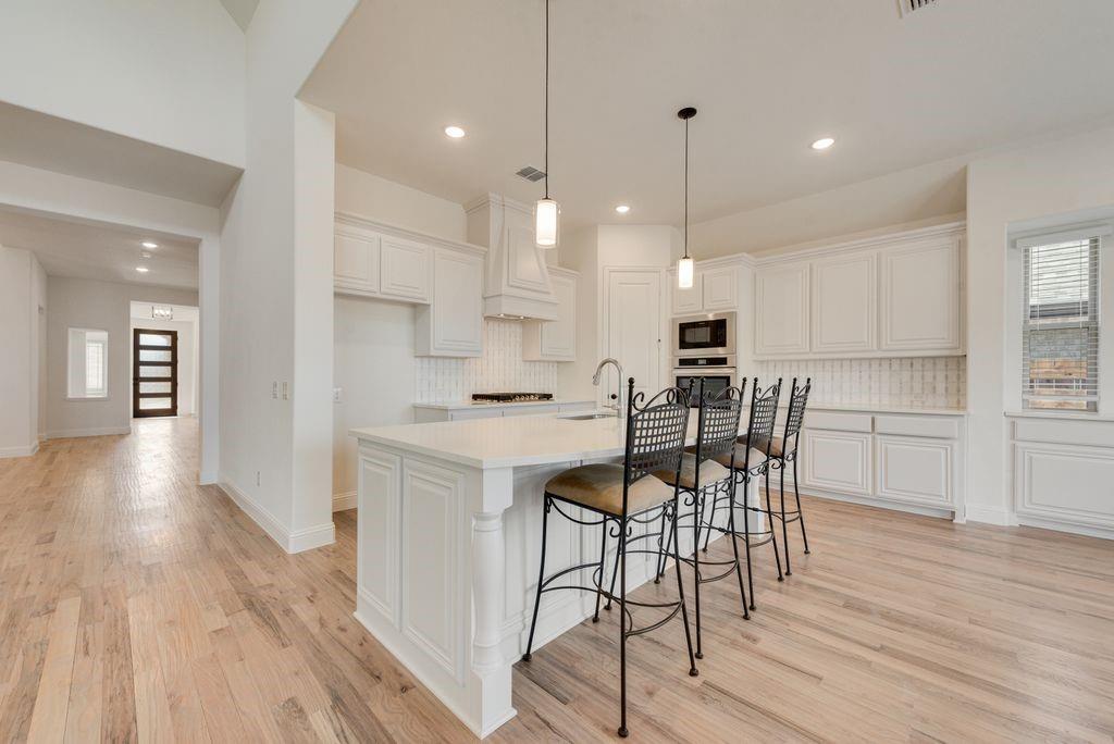 809 Turnbull Avenue Justin, TX 76247 - Photo 7 of 22 a kitchen with stainless steel appliances a dining table chairs stove refrigerator and cabinets